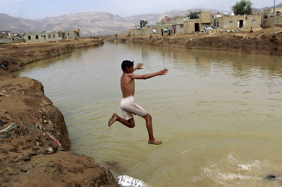 A Yemeni boy dives into a flooded field following heavy rain fall, in the city of Amran, 50 kms north of Sanaa, on April 15, 2016. A Yemeni boy dives into a flooded field following heavy rain fall, in the city of Amran, 50 kms north of Sanaa, on April 15, 2016.