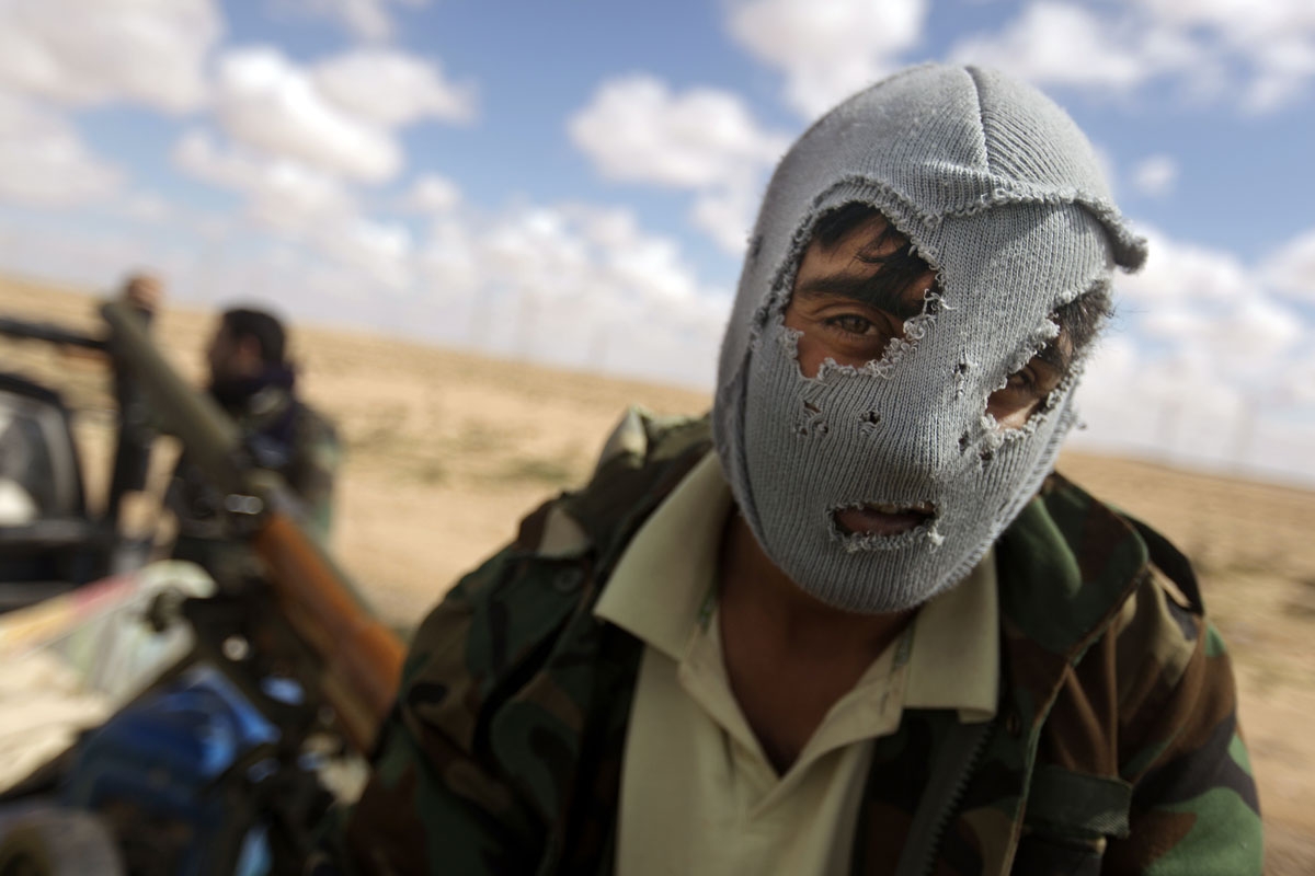 A Libyan rebel sits on the back of a pick up truck as rebel forces massed a second day on several kilometres from the key city of Ajdabiya