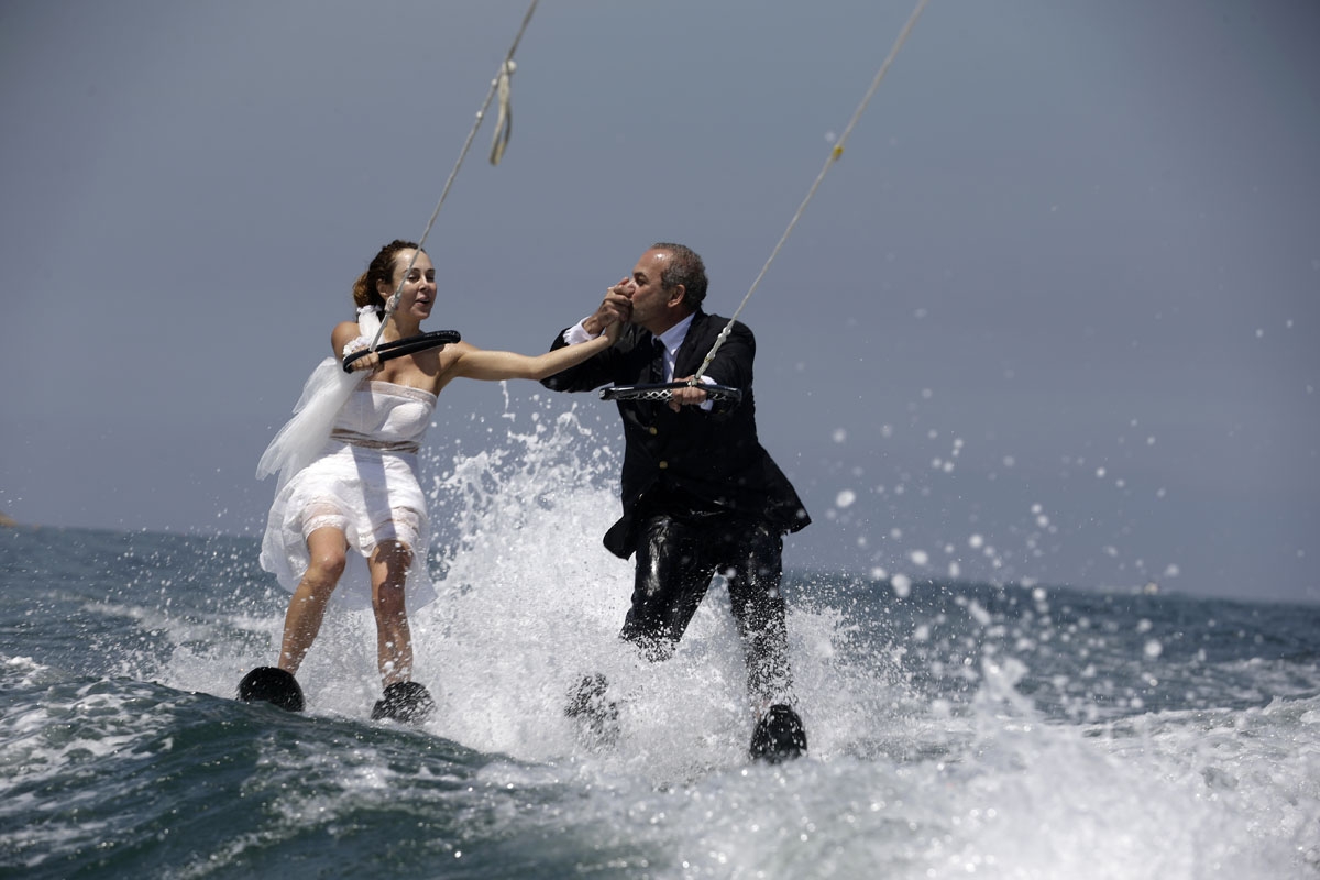 Lebanese groom Tommy kisses the hand of his bride Nadine's while water skiing dressed in their wedding clothes in the waters off the bay of Jounieh, north of Beirut, on May 29, 2017.