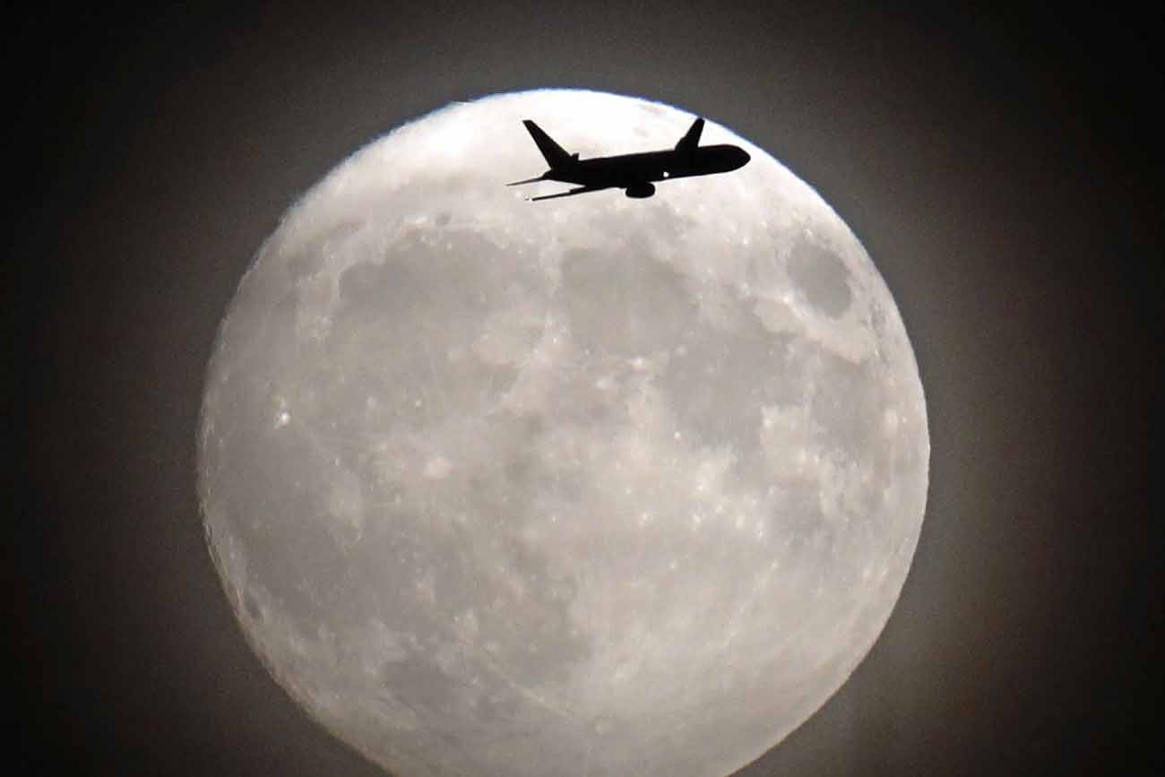 A commerical jet flies in front of the moon on its approach to Heathrow airport in west London on November 13, 2016.