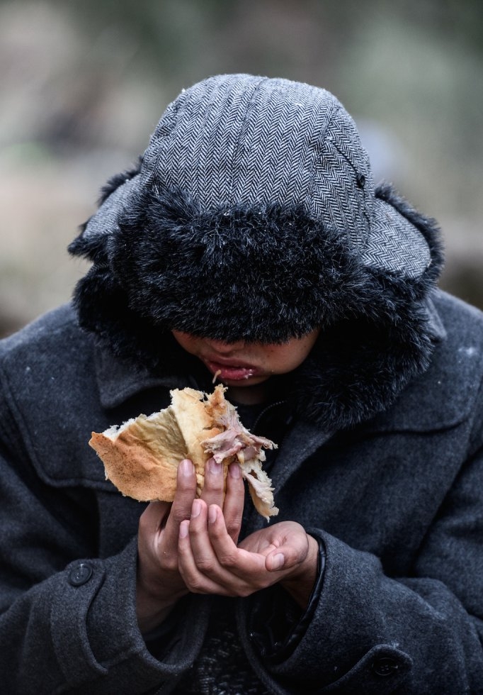 A refugee boy eats while camping after migrants were cheated by smugglers. January 29, 2016. A refugee boy eats while camping after migrants were cheated by smugglers. January 29, 2016.