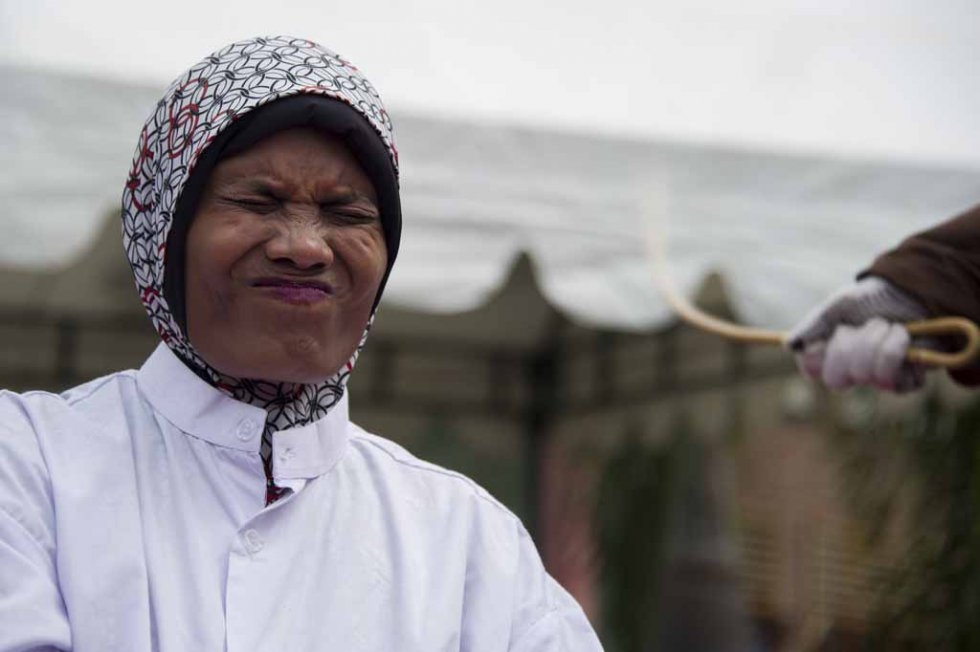 An Acehnese woman convicted for pimping reacts while lashed by a hooded local government officer during a public caning at a square in Banda Aceh, Aceh province, on June 12, 2015. (AFP PHOTO / Chaideer MAHYUDDIN) An Acehnese woman convicted for pimping reacts while lashed by a hooded local government officer during a public caning at a square in Banda Aceh, Aceh province, on June 12, 2015. (AFP PHOTO / Chaideer MAHYUDDIN)