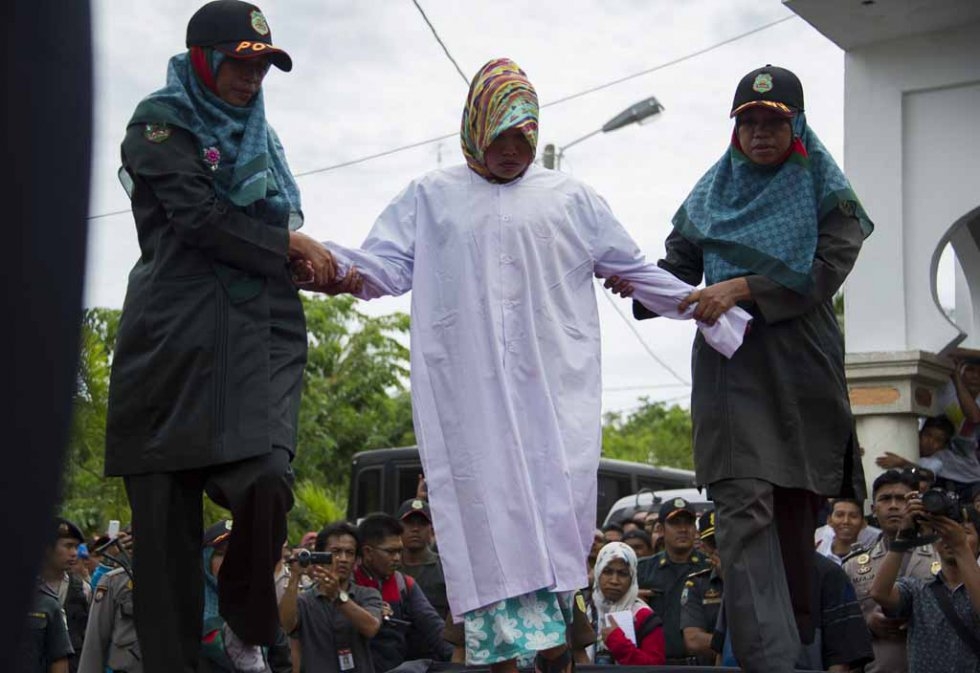 An Acehnese woman convicted for 'immoral acts' prepares for her punishment to be administered by a hooded local government officer during a public caning at a square in Banda Aceh, Aceh province, on June 12, 2015. (AFP PHOTO / Chaideer MAHYUDDIN) An Acehnese woman convicted for 'immoral acts' prepares for her punishment to be administered by a hooded local government officer during a public caning at a square in Banda Aceh, Aceh province, on June 12, 2015. (AFP PHOTO / Chaideer MAHYUDDIN)