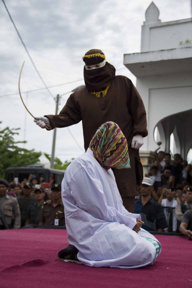 An Acehnese woman convicted for 'immoral acts' reacts while lashed by a hooded local government officer during a public caning at a square in Banda Aceh, Aceh province, on June 12, 2015. (AFP PHOTO / Chaideer MAHYUDDIN) An Acehnese woman convicted for 'immoral acts' reacts while lashed by a hooded local government officer during a public caning at a square in Banda Aceh, Aceh province, on June 12, 2015. (AFP PHOTO / Chaideer MAHYUDDIN)