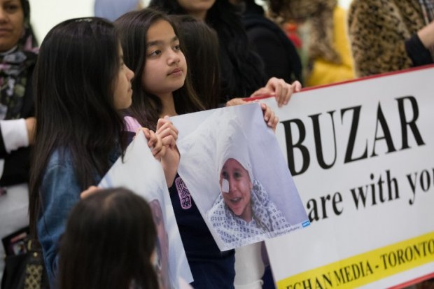 Family and well wishers hold portraits of Abuzar Ahmad as they await the child's arrival at Pearson Airport in Toronto, Ontario, Canada, on April 30, 2014 Family and well wishers hold portraits of Abuzar Ahmad as they await the child's arrival at Pearson Airport in Toronto, Ontario, Canada, on April 30, 2014