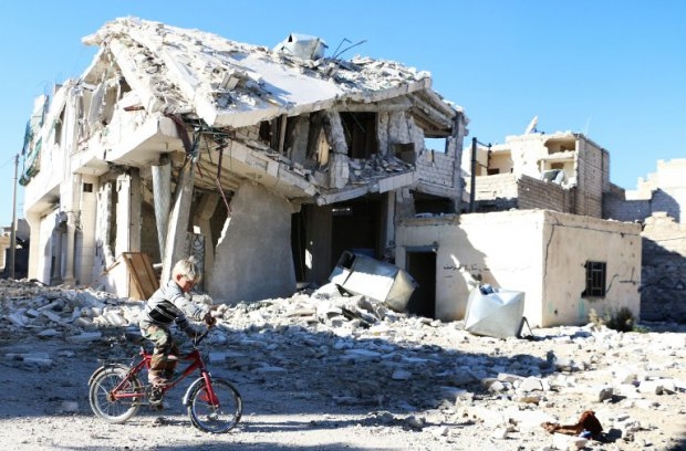 A boy rides his bike past a destroyed building in Aleppo on November 5, 2014 A boy rides his bike past a destroyed building in Aleppo on November 5, 2014