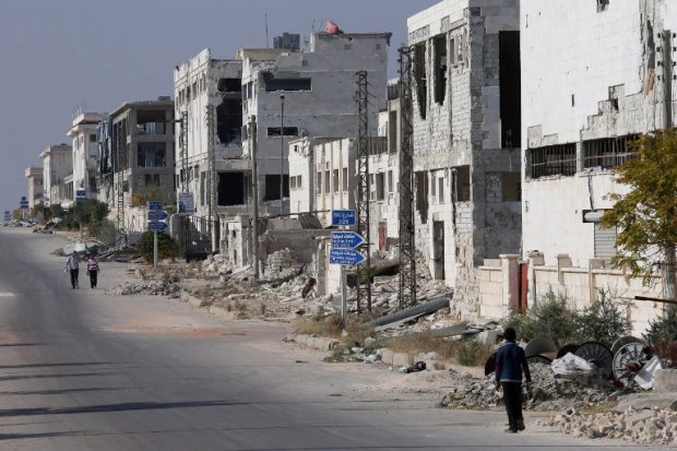 Syrians walk past destroyed buildings in Aleppo's government-held industrial area on November 18, 2014 Syrians walk past destroyed buildings in Aleppo's government-held industrial area on November 18, 2014