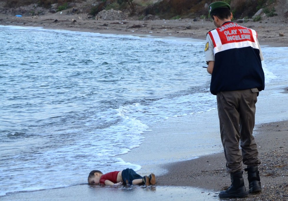 A Turkish police officer stands next to a migrant child who drowned off Bodrum, southern Turkey, on September 2, 2015 A Turkish police officer stands next to a migrant child who drowned off Bodrum, southern Turkey, on September 2, 2015