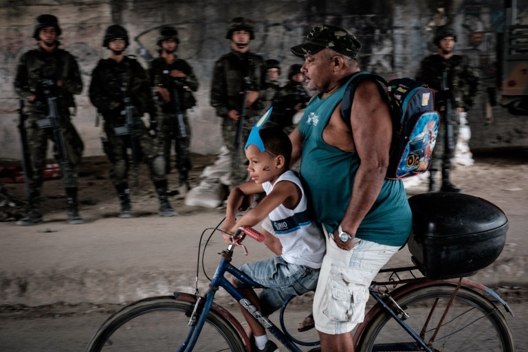 A man and boy pass in front of soldiers of the Brazilian Army as they take positions at a checkpoint during a security operation at Mare Complex shantytown in Rio de Janeiro, Brazil, on April 1, 2015 A man and boy pass in front of soldiers of the Brazilian Army as they take positions at a checkpoint during a security operation at Mare Complex shantytown in Rio de Janeiro, Brazil, on April 1, 2015