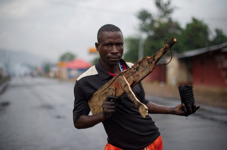 A man poses with a wooden rifle in the Musaga neighbourhood in Bujumbura on May 5, 2015 A man poses with a wooden rifle in the Musaga neighbourhood in Bujumbura on May 5, 2015