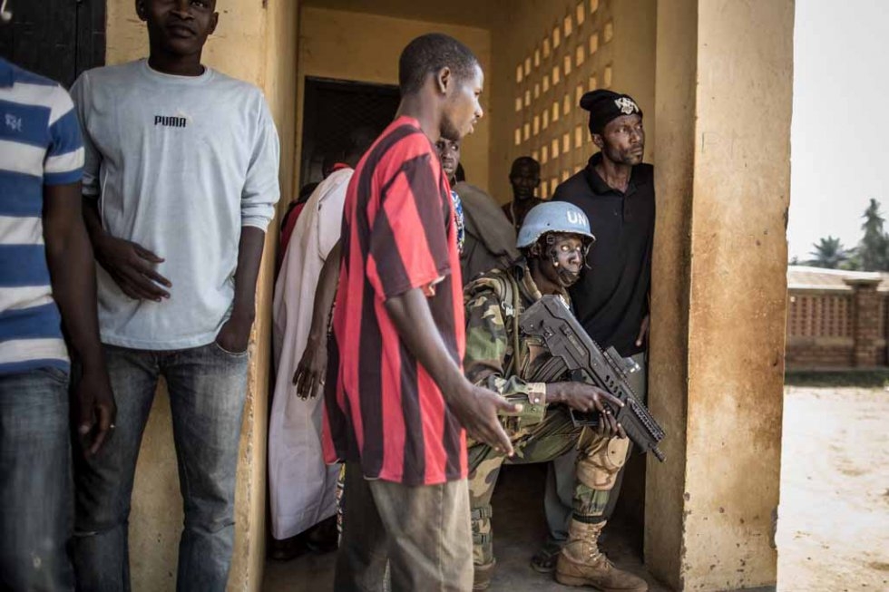 A UN soldier takes cover with civilians amid the gunfire at the school. A UN soldier takes cover with civilians amid the gunfire at the school.