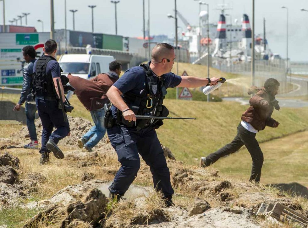 French riot police prevent migrants from sneaking onto trucks heading to England French riot police prevent migrants from sneaking onto trucks heading to England