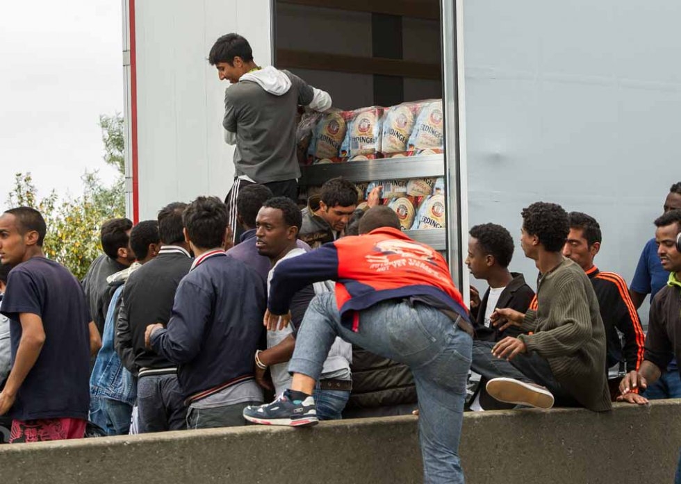 Migrants hop onto a truck heading for England Migrants hop onto a truck heading for England