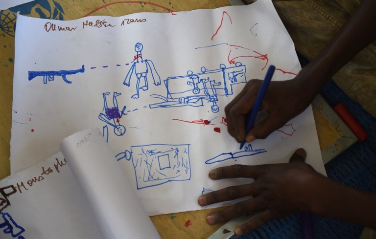 A Young Nigerian refugee draws an attack scene during a workshop at a camp near Baga Sola on April 6, 2015 A Young Nigerian refugee draws an attack scene during a workshop at a camp near Baga Sola on April 6, 2015