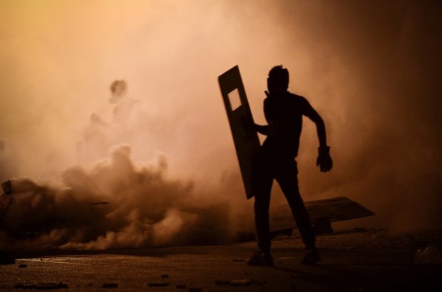 A Bahraini protestor stands amidst tear gas fired by riot police during clashes following a protest against the ruling regime in the village of Diraz, west of Manama, late on July 25, 2013 A Bahraini protestor stands amidst tear gas fired by riot police during clashes following a protest against the ruling regime in the village of Diraz, west of Manama, late on July 25, 2013