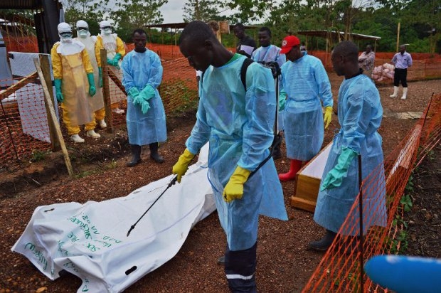 Sierra Leonese government burial team members disinfect the body bag of an Ebola victim at the Medecins Sans Frontieres Sierra Leonese government burial team members disinfect the body bag of an Ebola victim at the Medecins Sans Frontieres