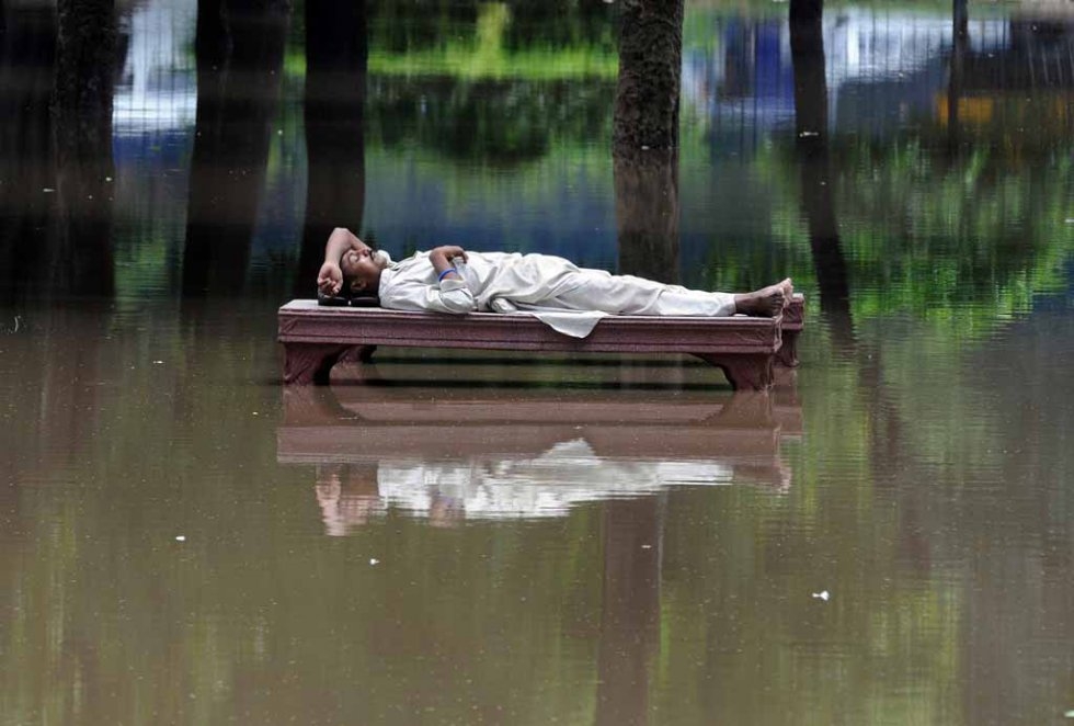 A man rests on a bench amid floodwater in Lahore, Pakistan. July, 2008. A man rests on a bench amid floodwater in Lahore, Pakistan. July, 2008.