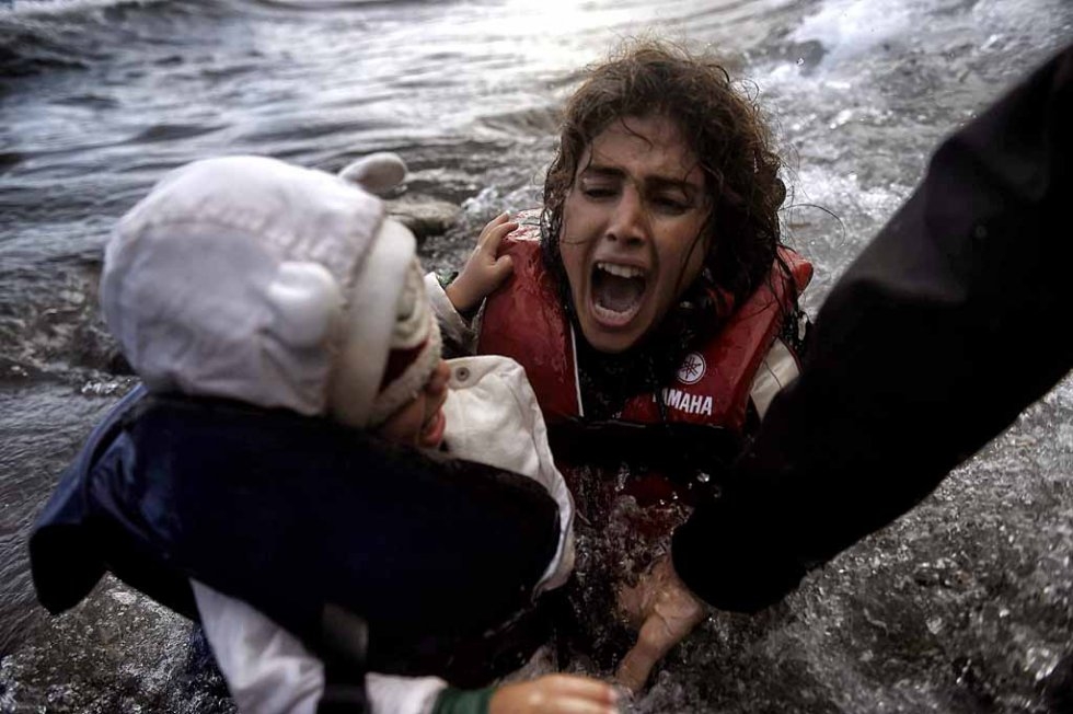 A woman falls into the water with her child at a Lesbos beach after crossing the Aegean sea from Turkey in October. (AFP/Aris Messinis) A woman falls into the water with her child at a Lesbos beach after crossing the Aegean sea from Turkey in October. (AFP/Aris Messinis)
