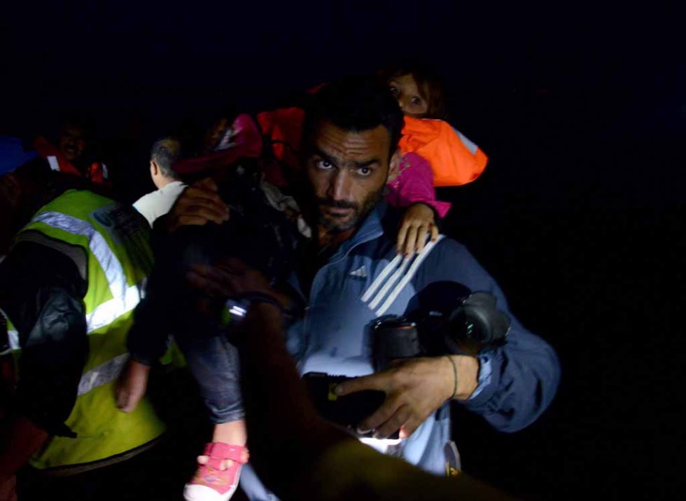 Aris Messinis carries a child in Lesbos in early October. Aris Messinis carries a child in Lesbos in early October.