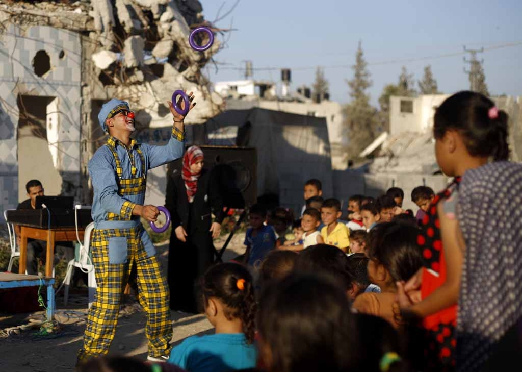 A clown performs for children in front of destroyed houses in Gaza City's Shujaiya neighbourhood on July 8, 2015 A clown performs for children in front of destroyed houses in Gaza City's Shujaiya neighbourhood on July 8, 2015