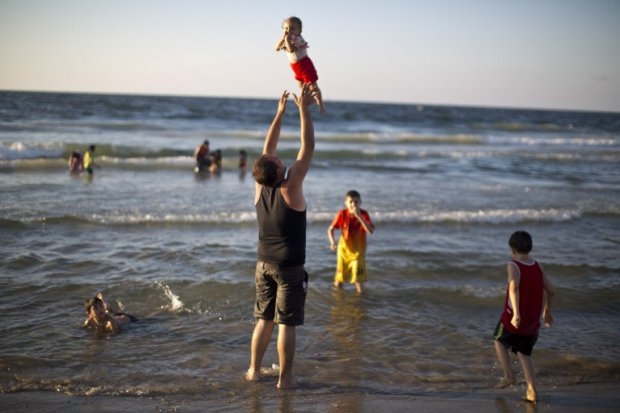 A Palestinian man plays with his baby on a Gaza beach on September 7, 2014 A Palestinian man plays with his baby on a Gaza beach on September 7, 2014
