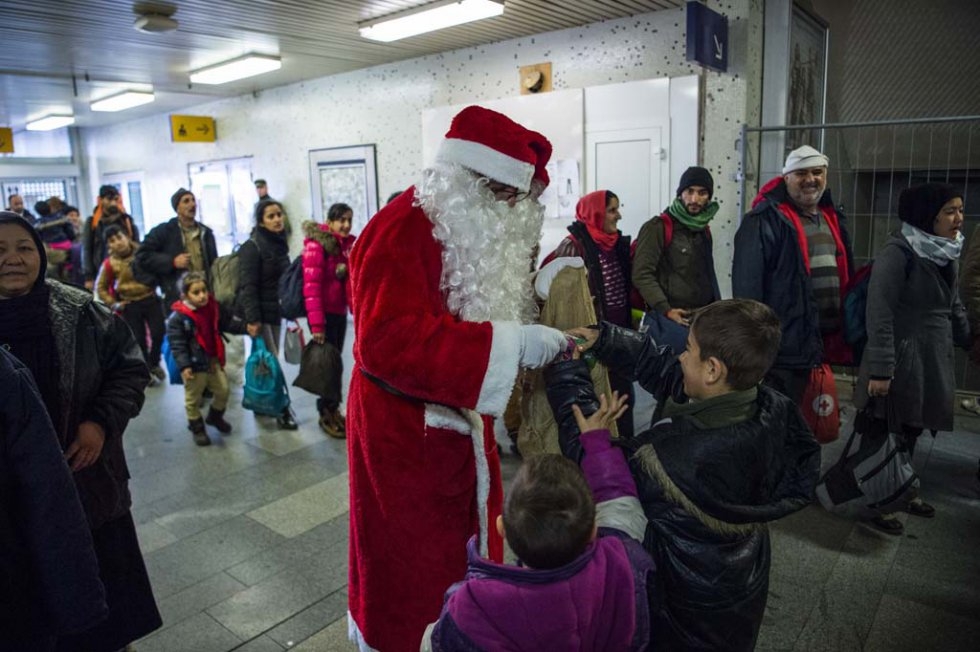 A volunteer Santa gives gifts to children of asylum seekers on December 24, 2015 at a train station near Berlin. A volunteer Santa gives gifts to children of asylum seekers on December 24, 2015 at a train station near Berlin.