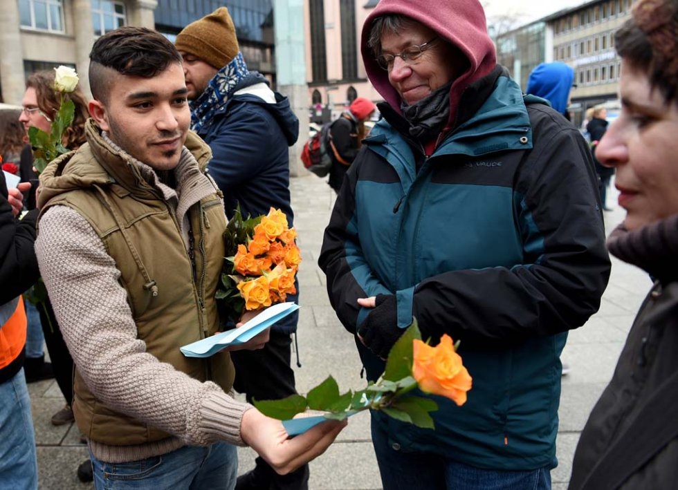 Syria refugees hand out flowers in front of Cologne's main train station. January 16, 2016. Syria refugees hand out flowers in front of Cologne's main train station. January 16, 2016.