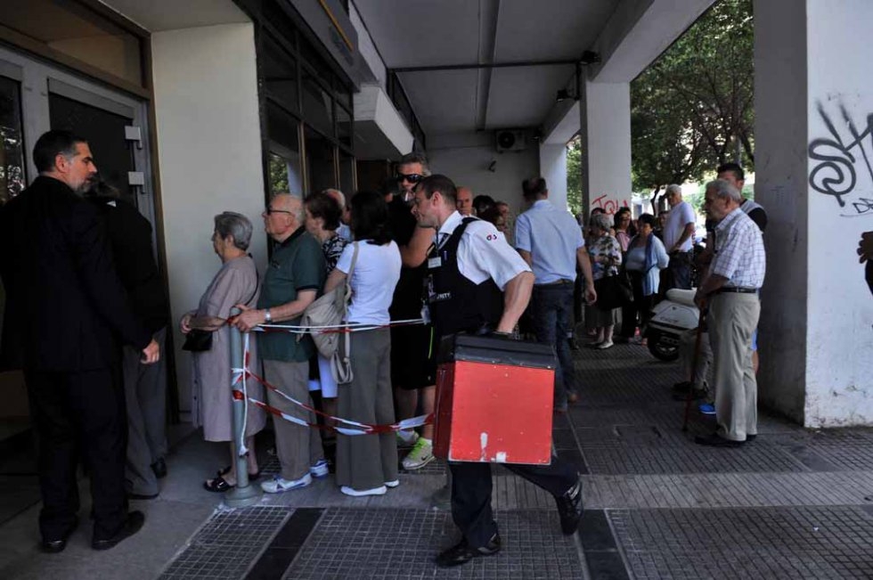 A security guard carries a case with cash as pensioners queue outside a national bank branch in Thessaloniki on July 3, 2015 A security guard carries a case with cash as pensioners queue outside a national bank branch in Thessaloniki on July 3, 2015