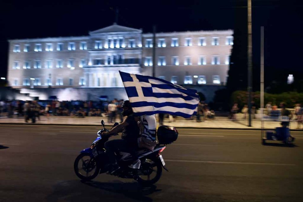 A motorcylist with his passenger holding a Greek flag passes in front of the Greek Parliament in Athens on July 5, 2015 ( AFP PHOTO / ARIS MESSINIS) A motorcylist with his passenger holding a Greek flag passes in front of the Greek Parliament in Athens on July 5, 2015 ( AFP PHOTO / ARIS MESSINIS)