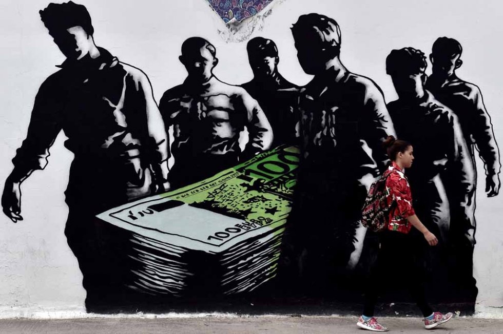 A young woman walks past a graffiti called 'Death of Euro' in Athens on June 19, 2015 A young woman walks past a graffiti called 'Death of Euro' in Athens on June 19, 2015