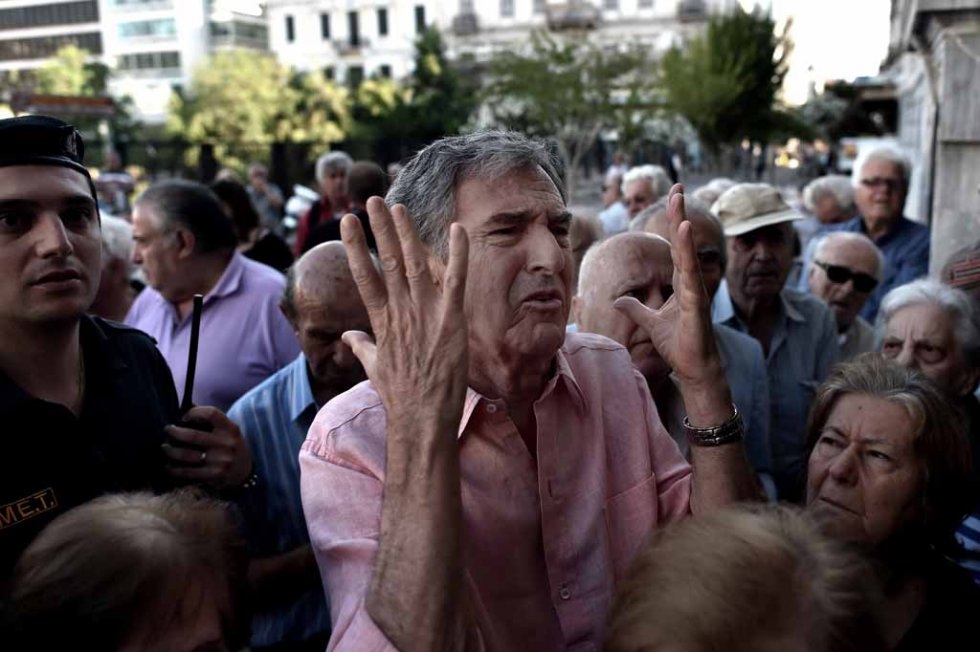 A man gestures as pensioners queue outside a national Bank branch, to cash out up to 120 euros in Athens on July 1, 2015 (AFP PHOTO / ARIS MESSINIS) A man gestures as pensioners queue outside a national Bank branch, to cash out up to 120 euros in Athens on July 1, 2015 (AFP PHOTO / ARIS MESSINIS)