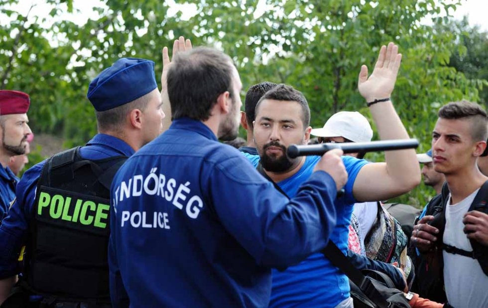 Police officers stop a group of migrants who broke out of the "collection point" near Röszke village on September 9, 2015 Police officers stop a group of migrants who broke out of the "collection point" near Röszke village on September 9, 2015