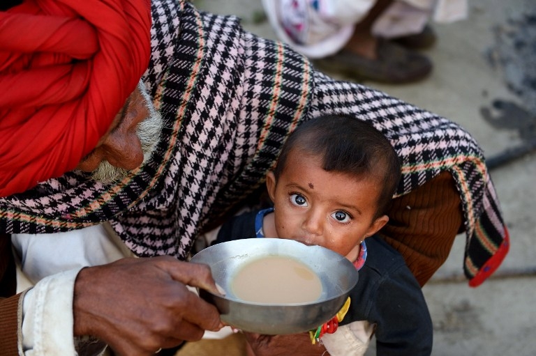 Nomadic shepherd Padma Ram helps his nine-month-old granddaughter Anu drink tea at his camp in Sikri in Faridabad on March 25, 2015 Nomadic shepherd Padma Ram helps his nine-month-old granddaughter Anu drink tea at his camp in Sikri in Faridabad on March 25, 2015