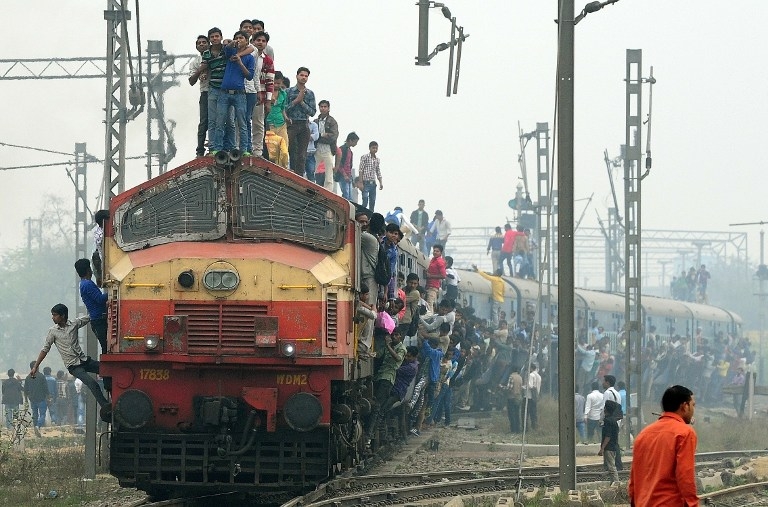 Passengers hang onto a train on the outskirts of New Delhi on February 25, 2015 Passengers hang onto a train on the outskirts of New Delhi on February 25, 2015