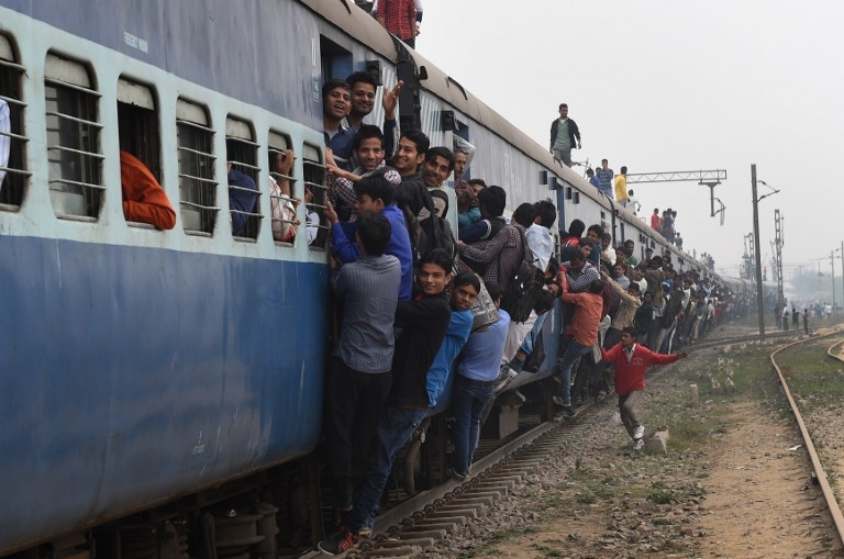 Passengers hang onto a train on the outskirts of New Delhi on February 25, 2015 Passengers hang onto a train on the outskirts of New Delhi on February 25, 2015