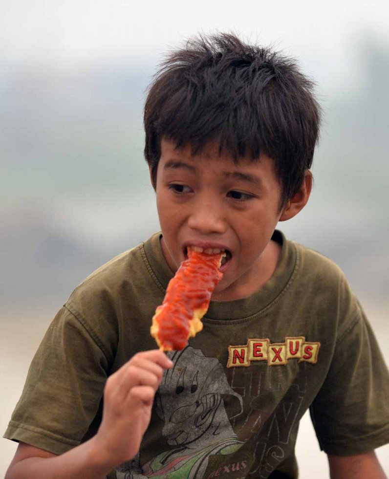 A boy eats a snack on the banks of the Kahayan river as air pollution levels descended to 'only' five times hazardous level limits. A boy eats a snack on the banks of the Kahayan river as air pollution levels descended to 'only' five times hazardous level limits.
