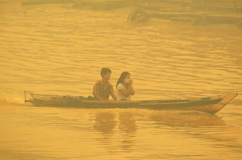 A couple crosses the river in Palangkaraya in October. A couple crosses the river in Palangkaraya in October.