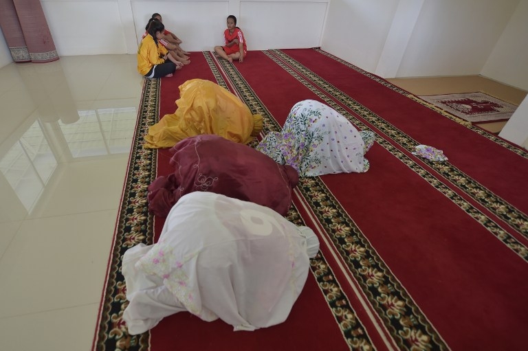 Women footballers pray before a training session in Jakarta on March 26, 2015 Women footballers pray before a training session in Jakarta on March 26, 2015