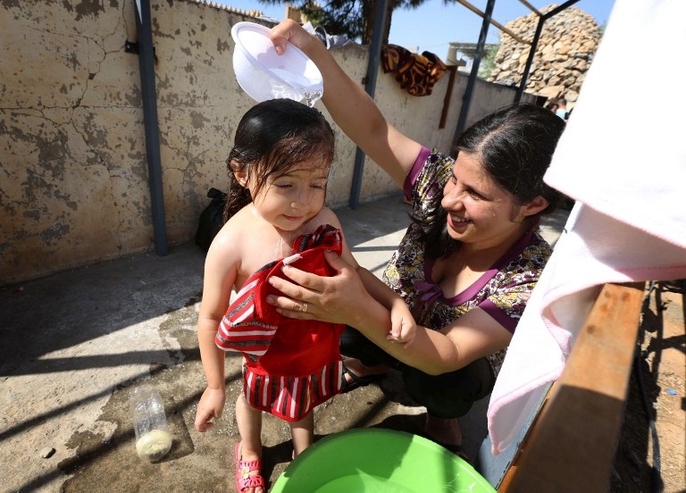 An Iraqi Christian refugee bathes her daughter in the yard of a church near Arbil on August 12, 2014 An Iraqi Christian refugee bathes her daughter in the yard of a church near Arbil on August 12, 2014