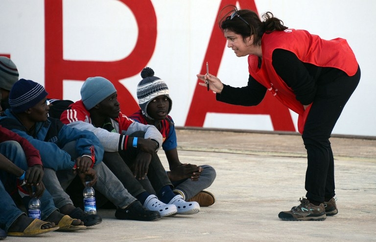 Shipwrecked migrants listen to an Red Cross worker after disembarking from a rescue vessel in the port of Augusta in Sicily on April 16, 2015 Shipwrecked migrants listen to an Red Cross worker after disembarking from a rescue vessel in the port of Augusta in Sicily on April 16, 2015