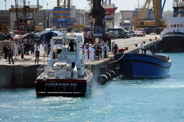 A fishing boat on which dozens of immigrants died, is towed by coast guards in the port of Pozzallo A fishing boat on which dozens of immigrants died, is towed by coast guards in the port of Pozzallo