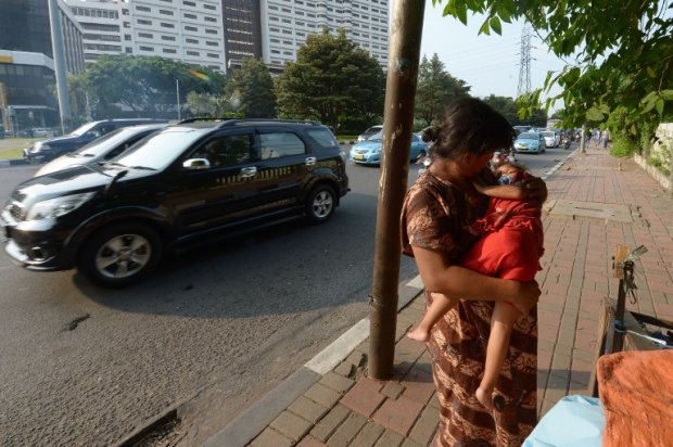 Indonesian homeless Rini cradles her daughter Ifah on a sidewalk in Jakarta on April 29, 2014 Indonesian homeless Rini cradles her daughter Ifah on a sidewalk in Jakarta on April 29, 2014