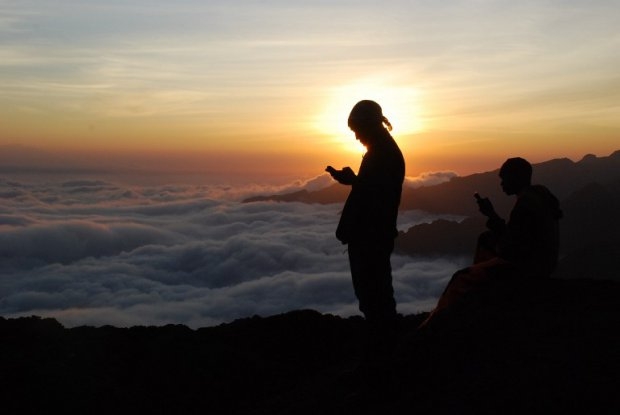 Tanzanian porters and guides stand on a rock half way up Kilimanjaro at sunset on September 21, 2014 trying to get a mobile phone signal to call their wives Tanzanian porters and guides stand on a rock half way up Kilimanjaro at sunset on September 21, 2014 trying to get a mobile phone signal to call their wives