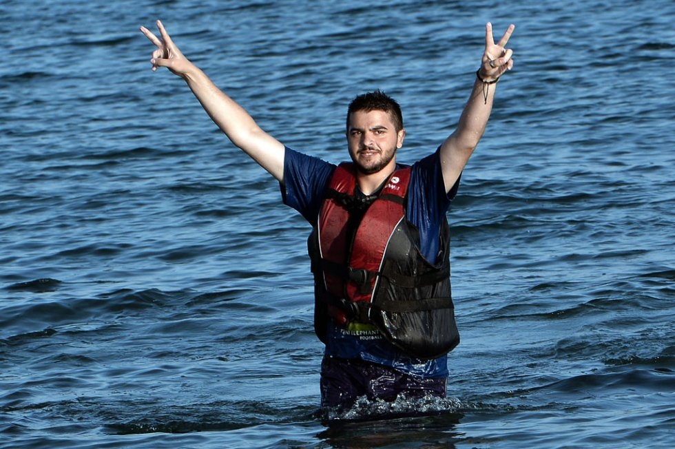 "A Syrian man flashes the V-sign after swimming to the shores of Kos from a half-sunk dinghy on August 17, 2015 "A Syrian man flashes the V-sign after swimming to the shores of Kos from a half-sunk dinghy on August 17, 2015