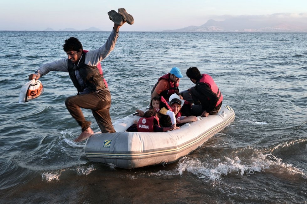 A migrant jumps off a small dinghy after arriving to the shores of the Greek island of Kos from Turkey on August 18, 2015 A migrant jumps off a small dinghy after arriving to the shores of the Greek island of Kos from Turkey on August 18, 2015