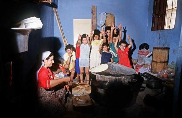 Palestinian children make the victory sign while a woman cooks bread in the refugee camp of Shatila,near Beirut, June 23, 1985 Palestinian children make the victory sign while a woman cooks bread in the refugee camp of Shatila,near Beirut, June 23, 1985