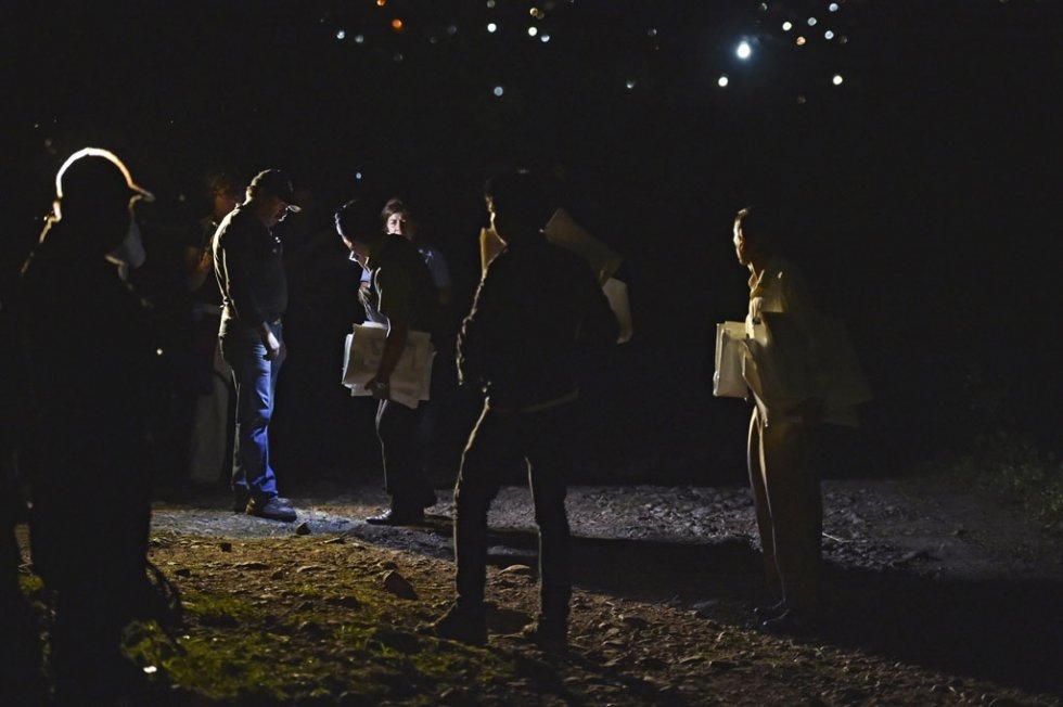 Policemen hold white body bags as they arrive at the site of a mass grave in the Guerrero state. October, 2014. (Yuri Cortez) Policemen hold white body bags as they arrive at the site of a mass grave in the Guerrero state. October, 2014. (Yuri Cortez)