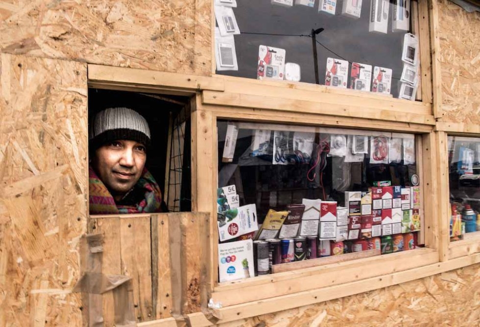 A Pakistani man looks out from his shop in the Jungle. January, 2016. A Pakistani man looks out from his shop in the Jungle. January, 2016.