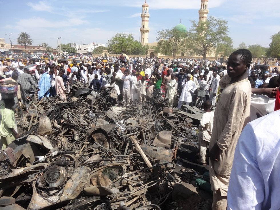 Residents outside the central mosque in Kano a day after gunfire and suicide blasts killed at least 120 people there. Residents outside the central mosque in Kano a day after gunfire and suicide blasts killed at least 120 people there.