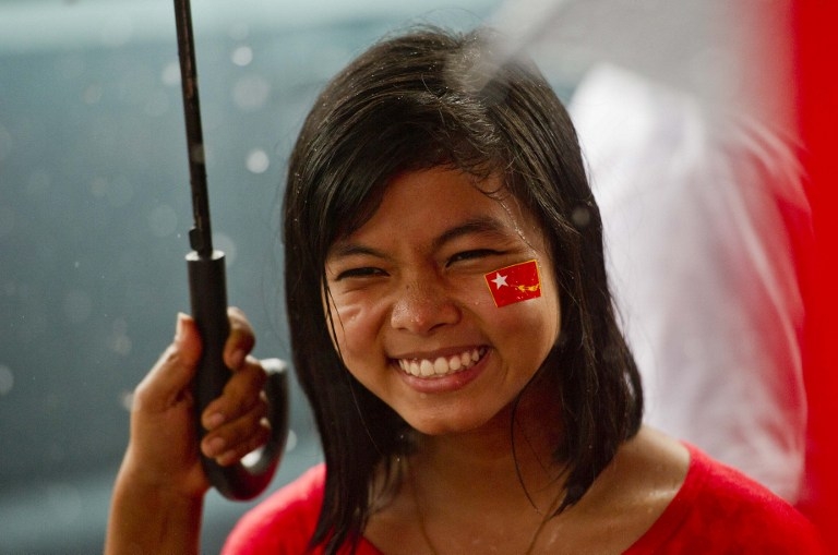 A supporter of Suu Kyi's party smiles as she watches the first official results of the November election announced on a giant screen outside party headquarters the day after the poll. A supporter of Suu Kyi's party smiles as she watches the first official results of the November election announced on a giant screen outside party headquarters the day after the poll.